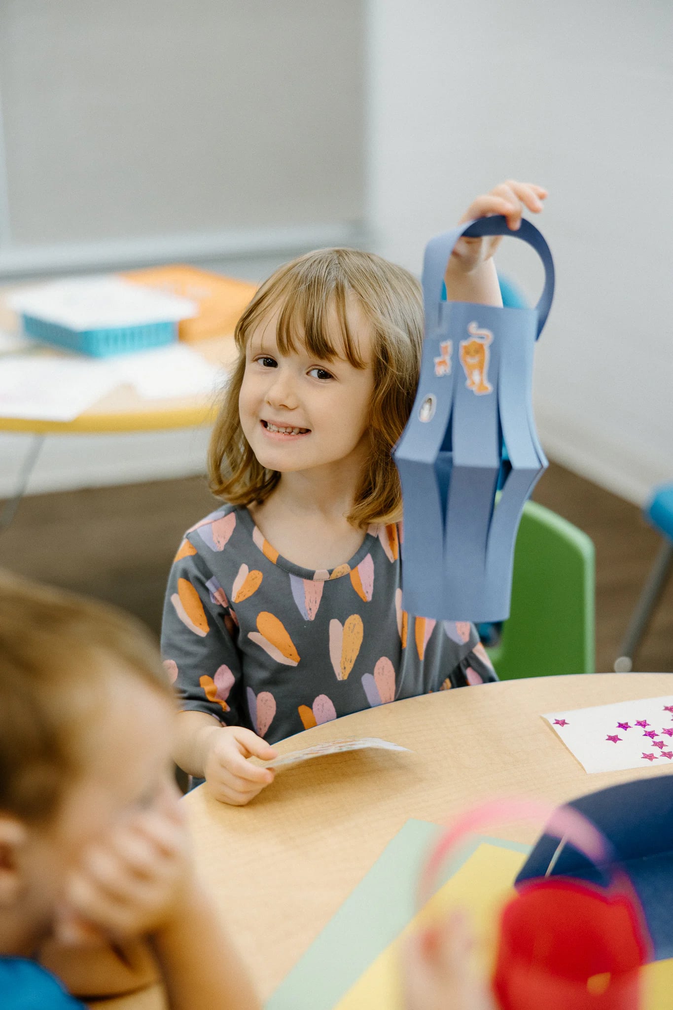 A girl holding up her craft at a kids table