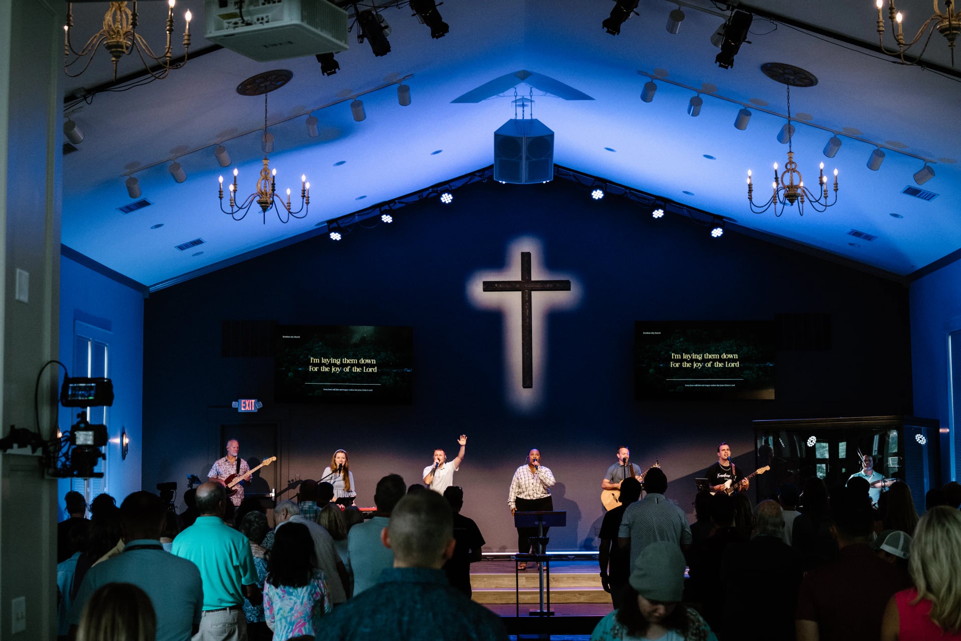 Worship beneath the blue-lit cross